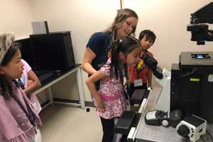 Young neuroscience student looks through magnifying glass at Brain Explorer Academy