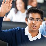 Student raises hand in lecture hall