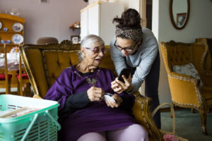 A Fun Way to Keep Your Memory Sharp - image of younger adult showing senior how to use phone