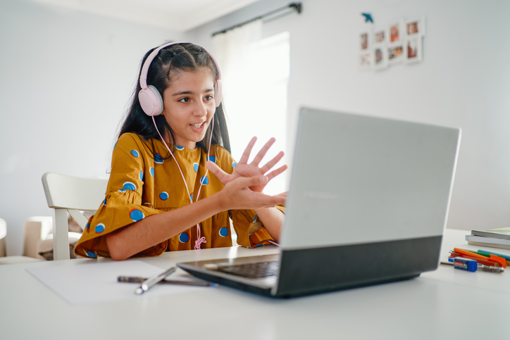 UCI Virtual Brain Camp - Image of Teenage girl with headphones and laptop having online school class at home