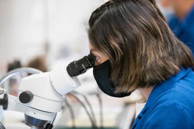 Image of neuroscience student looking through microscope in Igarashi Lab