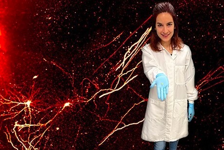 Scientist poses in from of neuron image.