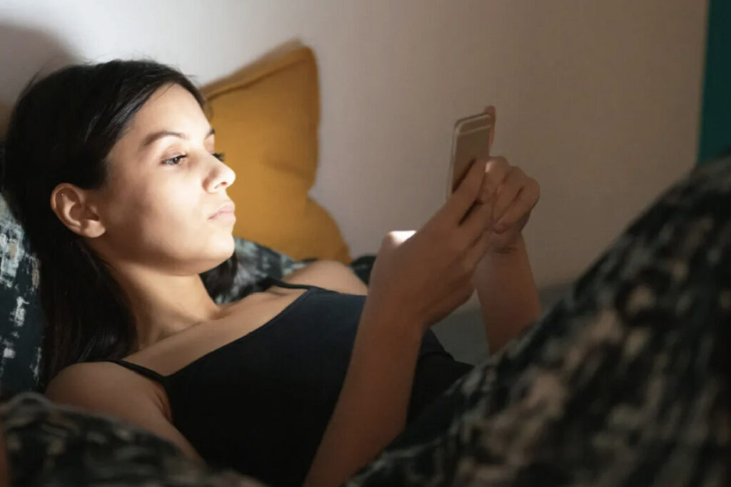 Why the Human Mind Is 'Not Designed' to Stay Awake Past Midnight - image of person looking at their phone in bed