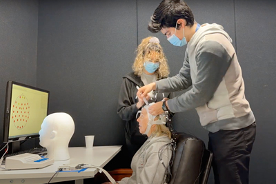 Graduate student Ashley Manley and research assistant Luis Parada Ramirez set up the EEG cap on a volunteer. 